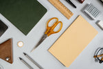 Flat lay showcasing various office supplies including scissors, notebook, ruler, and pencil.